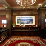 Resepsionis hotel melayani tamu di meja front office dengan dekorasi mewah dan lampu gantung